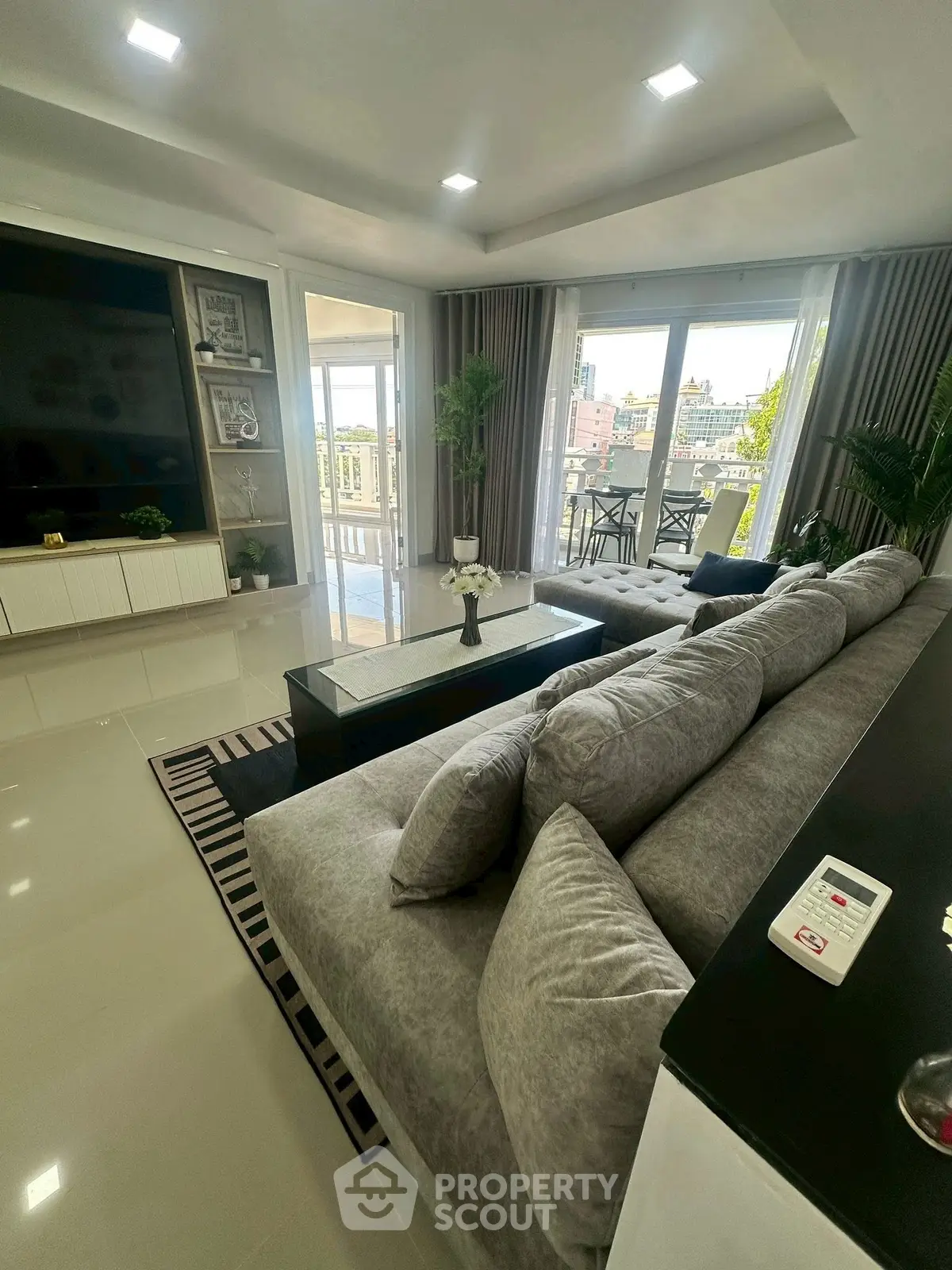 Spacious modern living room with large sofa and balcony view, perfect for relaxation.