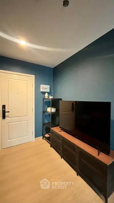 Modern living room with sleek TV setup and stylish blue accent wall.