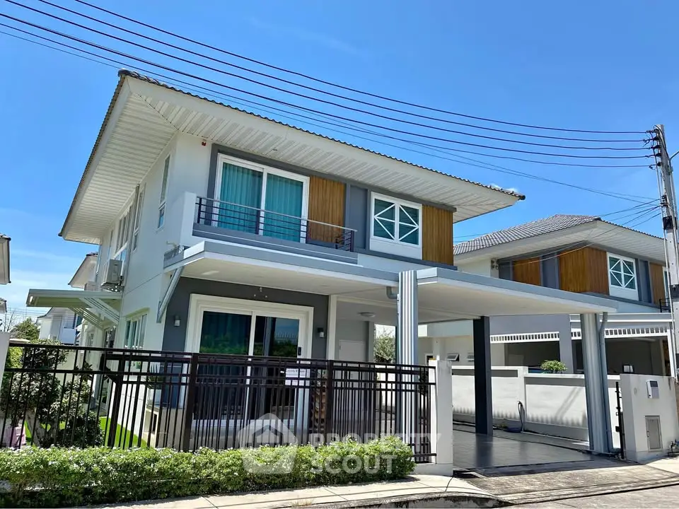 Modern two-story house with sleek design and spacious driveway under clear blue sky.