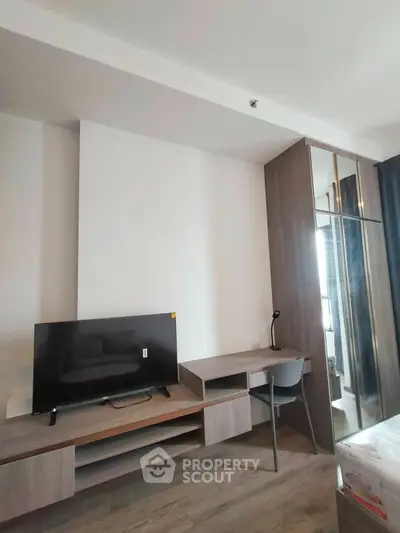 Modern study area with sleek desk, chair, and TV in a stylish apartment.