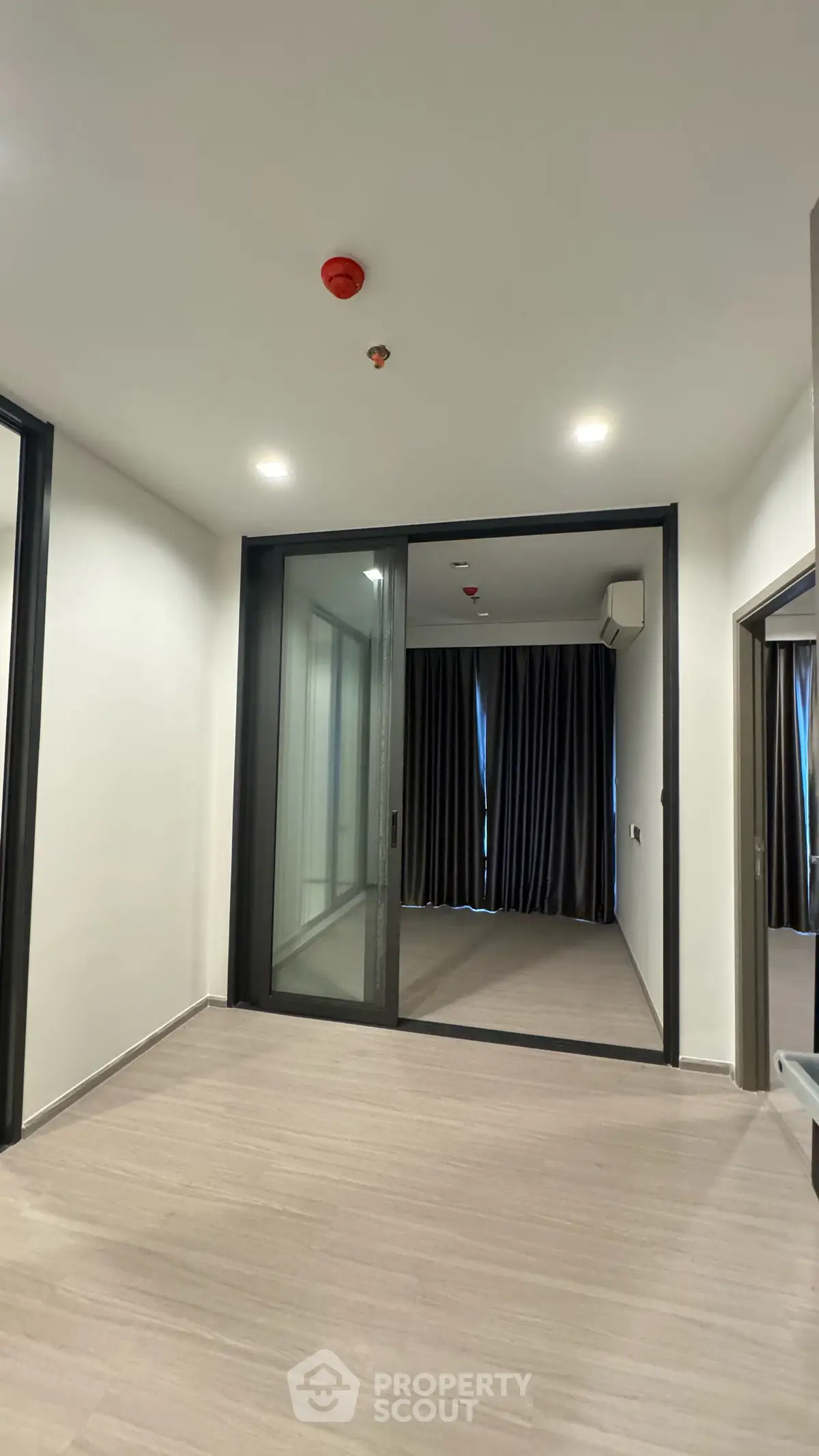 Spacious modern interior with sliding glass doors and elegant curtains, perfect for versatile living space.