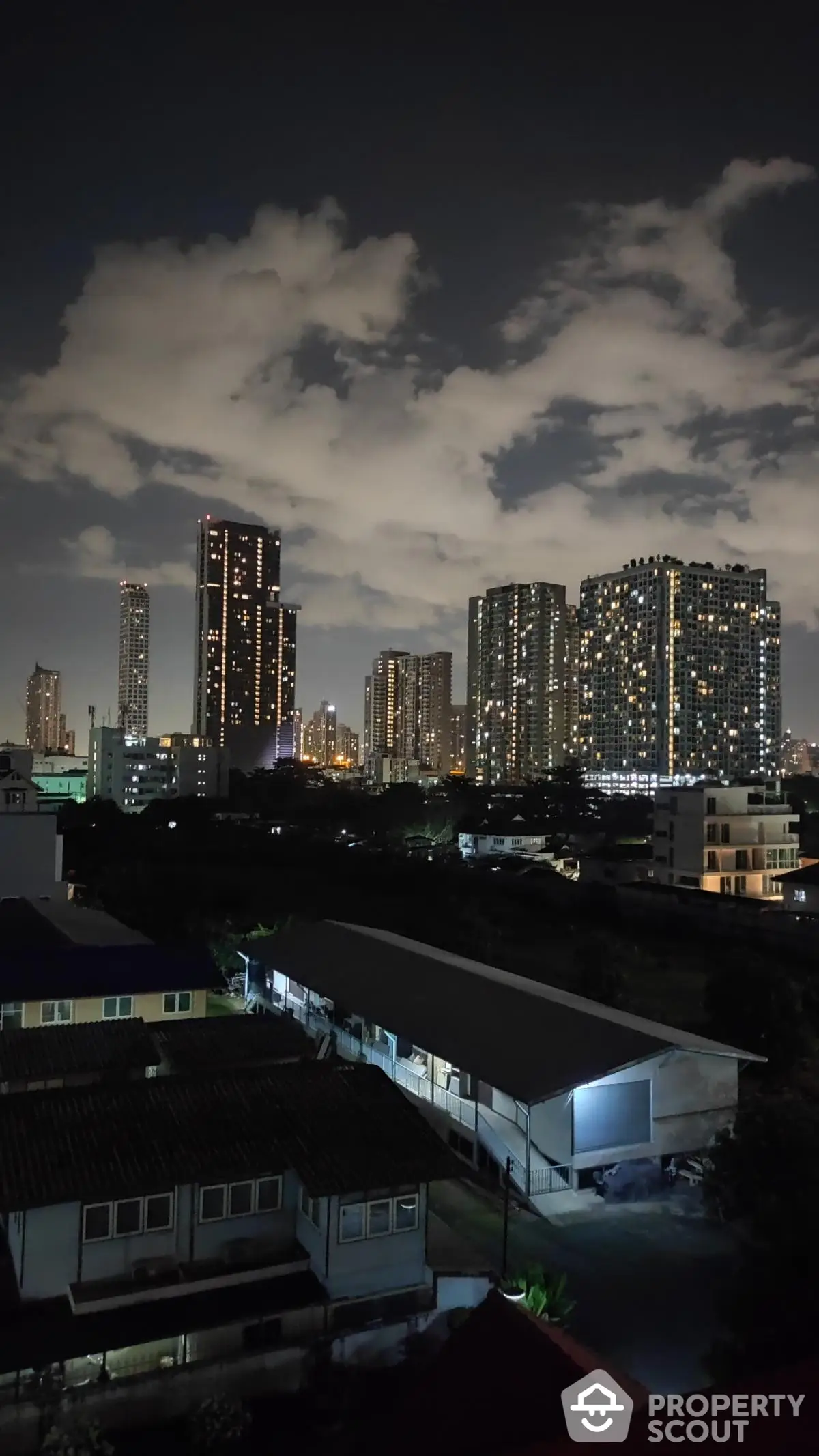 Stunning city skyline view at night with illuminated skyscrapers and cloudy sky