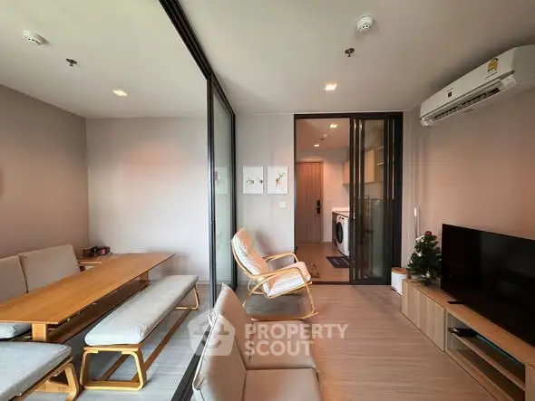 Modern living room with stylish furniture and open view to laundry area, featuring sleek design and cozy ambiance.
