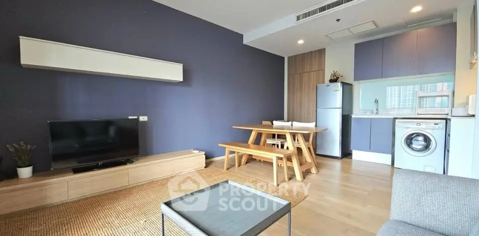 Modern living room with open kitchen, featuring sleek furniture and appliances in a stylish apartment.