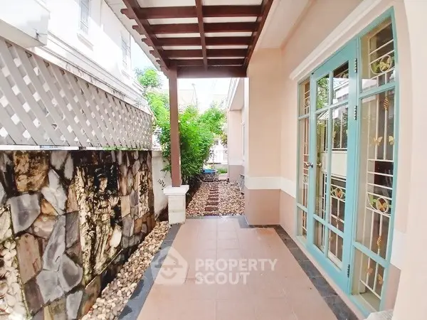 Charming patio with stone wall and elegant glass doors in a cozy residential setting.