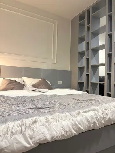 Modern bedroom with stylish shelving and cozy bedding in a contemporary apartment.