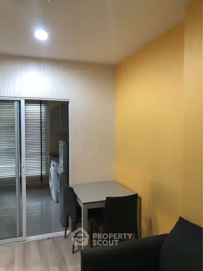 Modern apartment interior with bright yellow accent wall and compact dining area.
