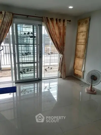 Spacious living room with large windows and elegant curtains, perfect for natural light.