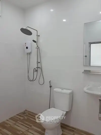 Modern bathroom with shower, toilet, and sleek white tiles.
