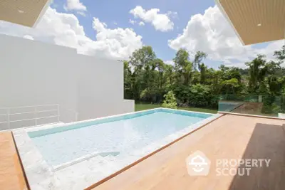 Luxurious modern home with private pool and scenic view of lush greenery.