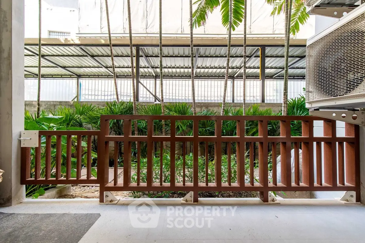 Modern garden view with wooden fence and lush greenery in urban setting.