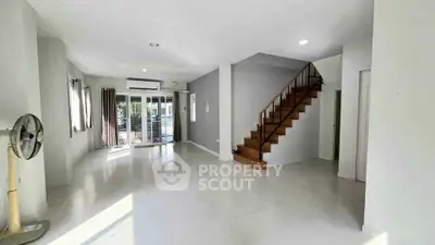 Spacious modern living room with staircase and large windows for natural light.