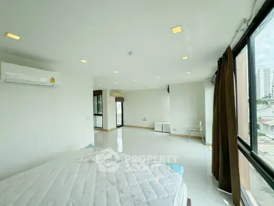 Spacious bedroom with large windows and city view, featuring modern lighting and air conditioning.