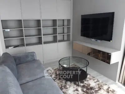 Modern living room with sleek shelving, wall-mounted TV, and cozy gray sofa.