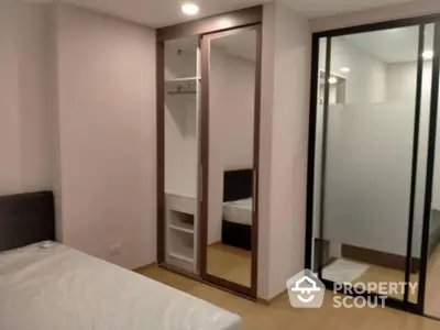 Cozy bedroom with large mirrored wardrobe and sliding glass doors leading to an en-suite bathroom, featuring warm lighting and wooden flooring.