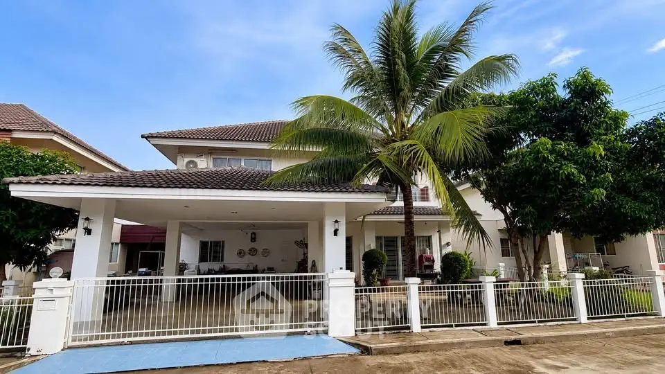Stunning two-story house with spacious driveway and lush palm tree in a serene neighborhood.