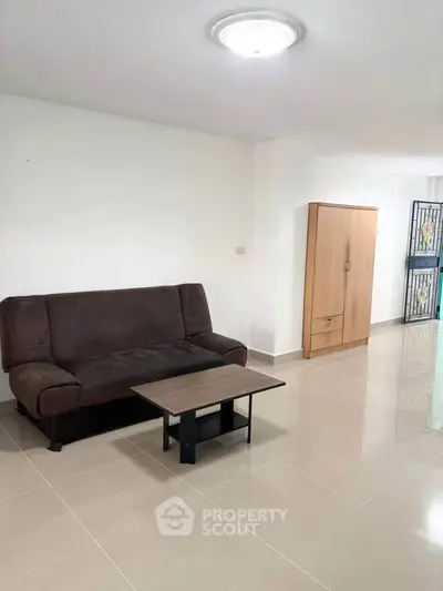 Spacious living room with modern sofa and sleek tile flooring, perfect for relaxation and entertaining.