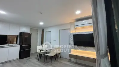 Modern open-plan living room with sleek kitchen and dining area, featuring stylish lighting and contemporary decor.