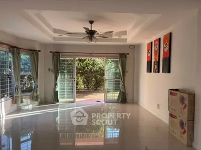 Spacious living room with large windows and garden view, perfect for natural light lovers.