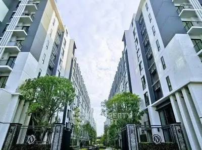 Modern apartment building exterior with lush greenery and clear sky view.