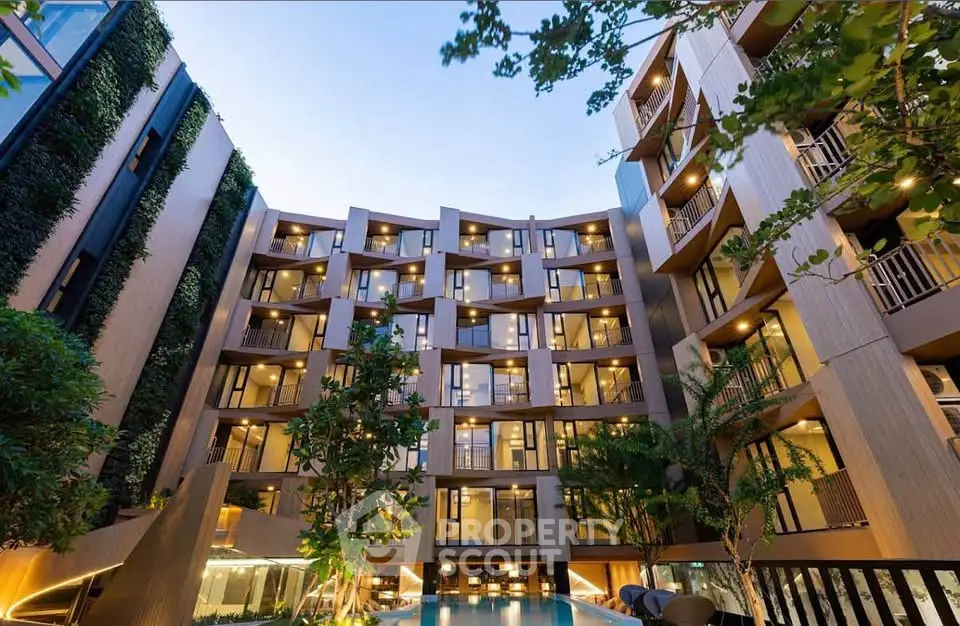 Modern apartment building with lush greenery and inviting pool area at dusk.