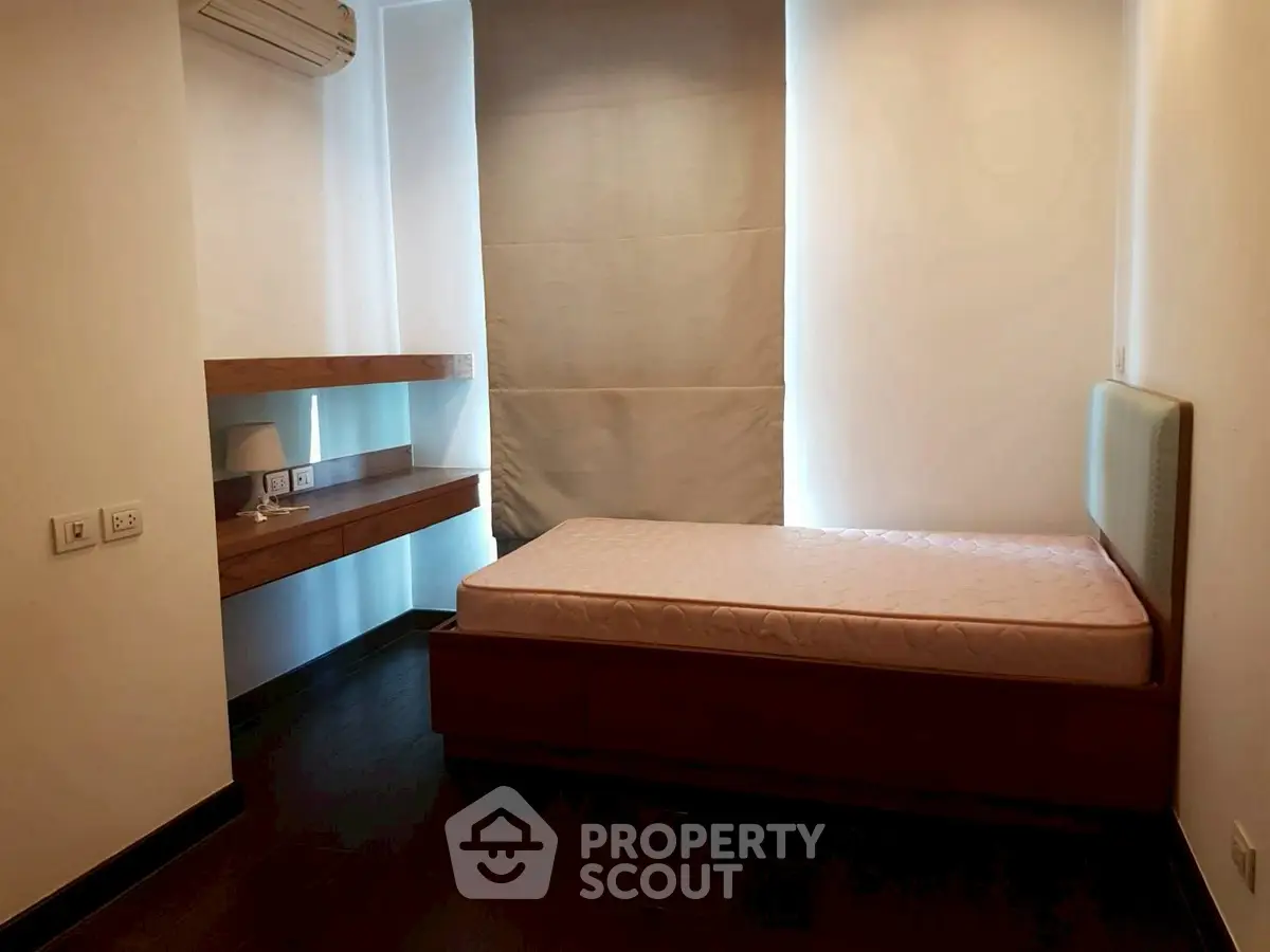 Cozy bedroom with minimalist design featuring a single bed and wooden shelves.