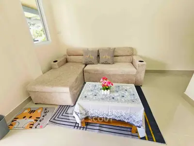 Cozy living room with beige sectional sofa and floral centerpiece on coffee table.