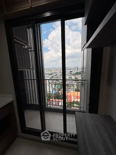 High-rise apartment balcony with stunning cityscape view through glass doors.