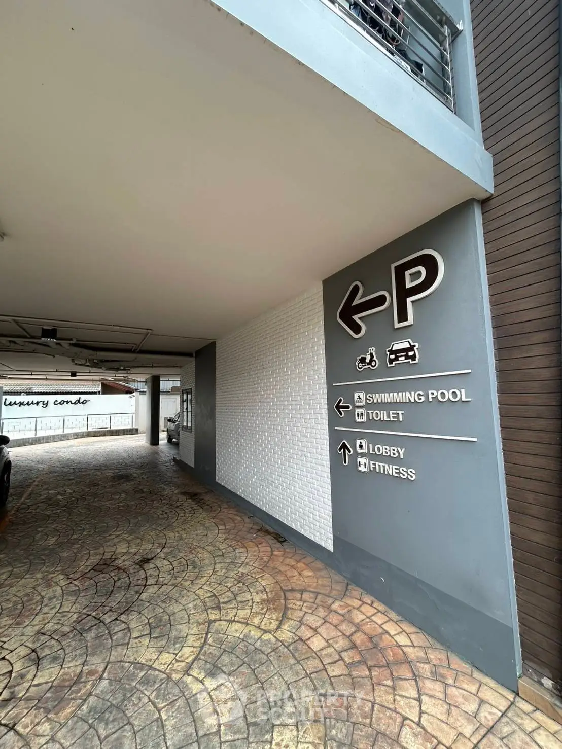 Modern condo parking area with directional signs to amenities like pool and fitness center.