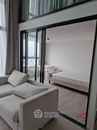 Modern apartment with open living room and bedroom featuring large windows and sleek design.