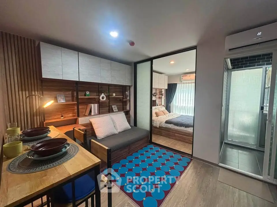 Modern studio apartment with cozy living area and bedroom separated by glass partition.