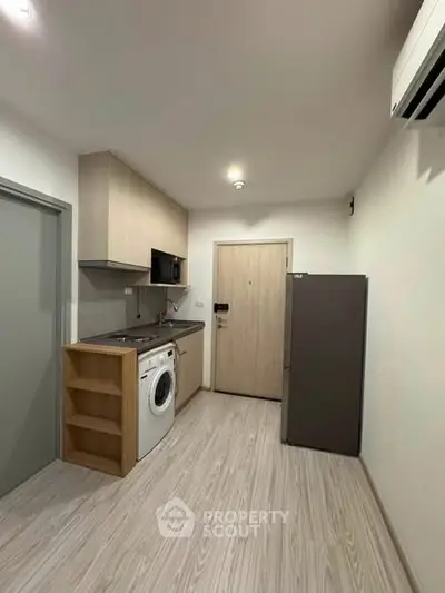 Modern compact kitchen with washing machine and fridge in a cozy apartment.