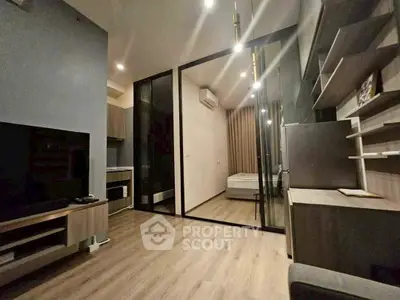 Modern open-plan living room with sleek kitchen and glass-walled bedroom