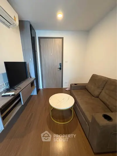 Cozy living room with modern sofa, TV, and stylish coffee table in a compact apartment.