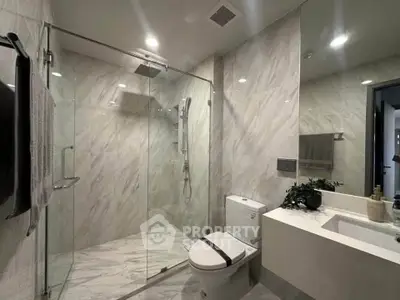Modern bathroom with glass shower and sleek fixtures in luxury apartment.