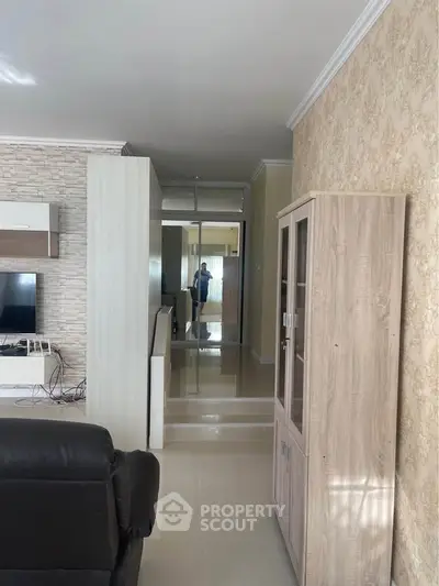 Spacious living room with modern decor and elegant wall finishes, featuring a sleek TV unit and comfortable seating.