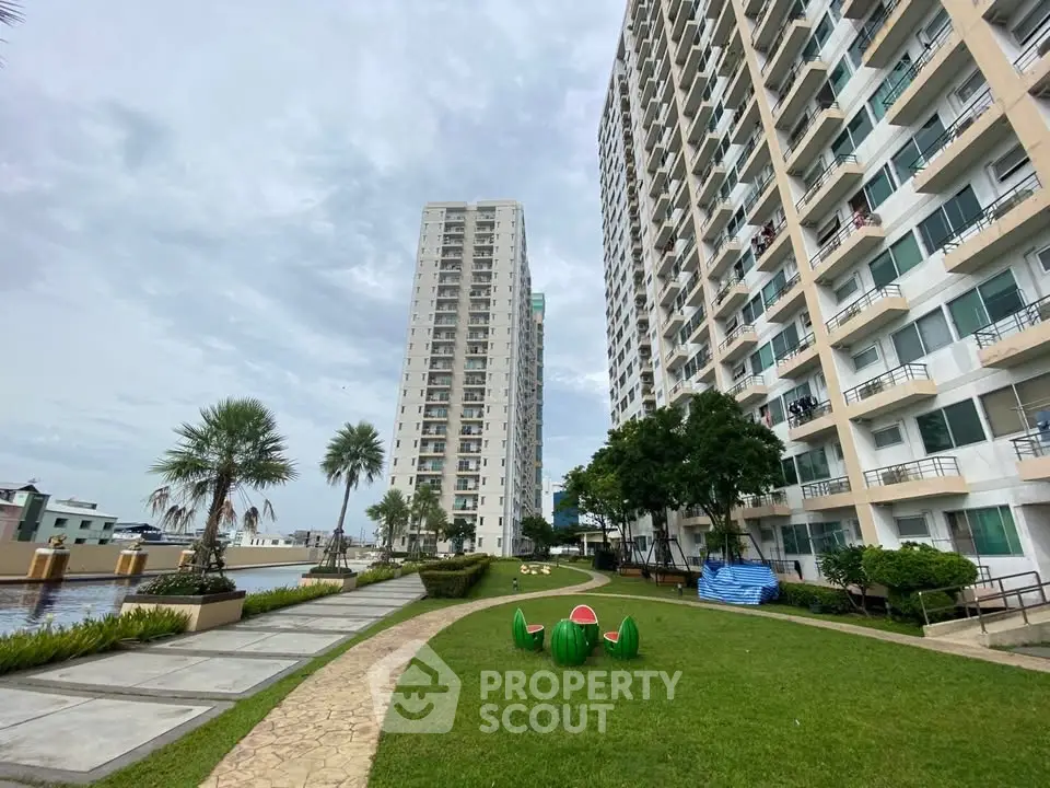 Modern high-rise apartment buildings with lush green garden and outdoor seating area.