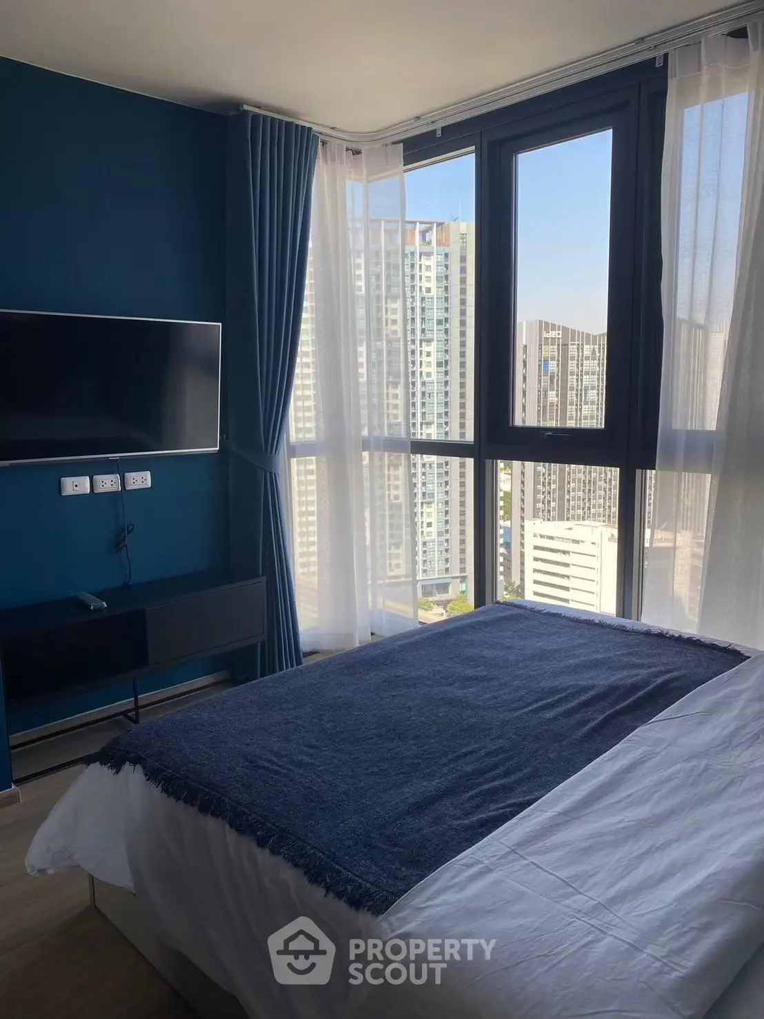 Modern bedroom with large windows offering stunning city views.