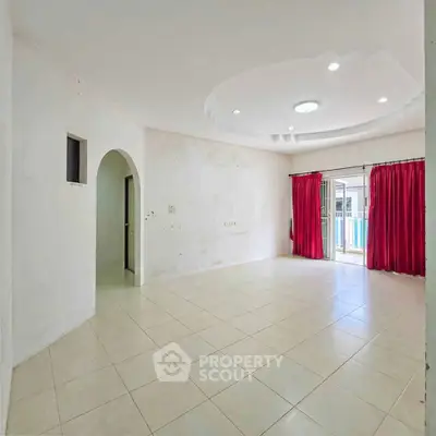 Spacious living room with tiled floor and red curtains, perfect for family gatherings.