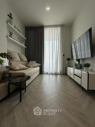 Modern living room with stylish decor, large TV, and elegant flooring