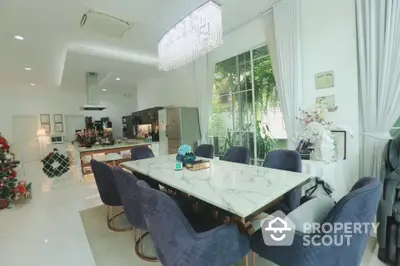 Luxurious dining area with elegant marble table, plush navy chairs, and modern kitchen in open layout design.