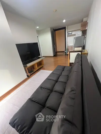 Modern living room with sleek black sofa and large TV, perfect for relaxation and entertainment.