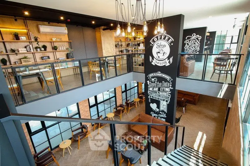 Modern two-story cafe with stylish decor and ample seating, featuring large windows and trendy lighting.