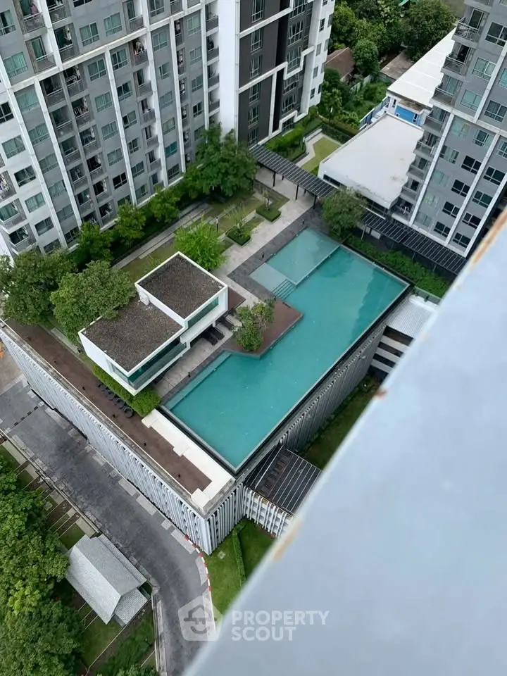 Stunning aerial view of modern apartment complex with luxurious pool and lush greenery.