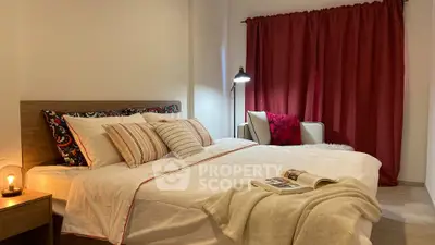 Cozy bedroom with elegant decor and warm lighting, featuring a comfortable bed and stylish red curtains.