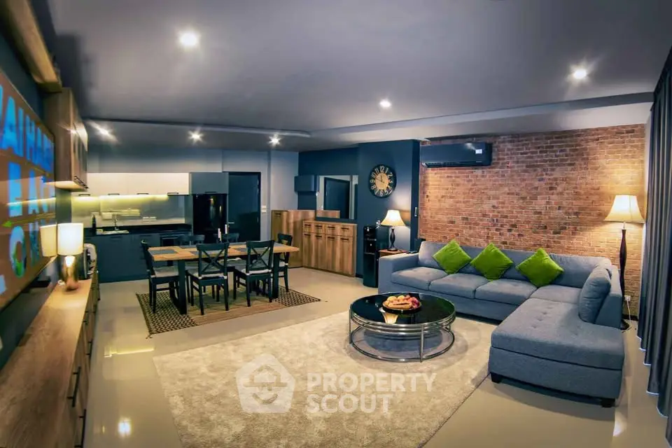 Modern living room with open kitchen, stylish decor, and cozy seating area.