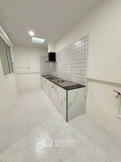 Modern minimalist kitchen with sleek white cabinetry and tiled backsplash in a compact layout.