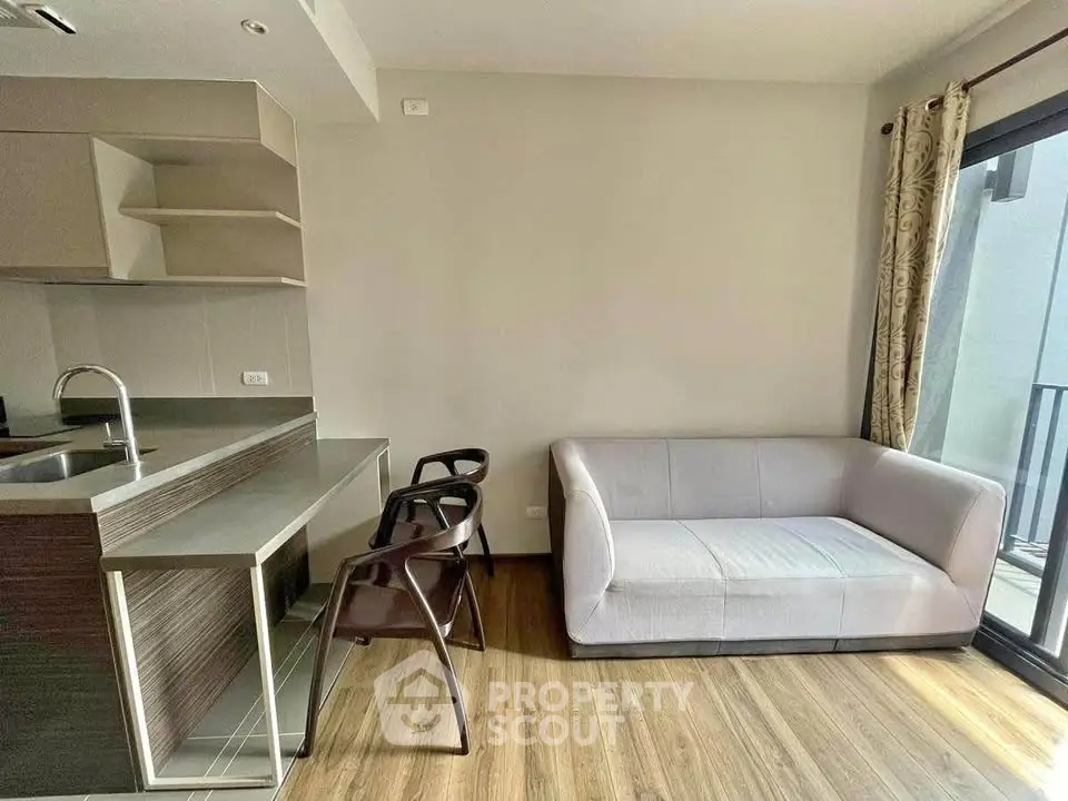 Modern living room with sleek kitchen and cozy sofa, featuring a minimalist design and natural light.