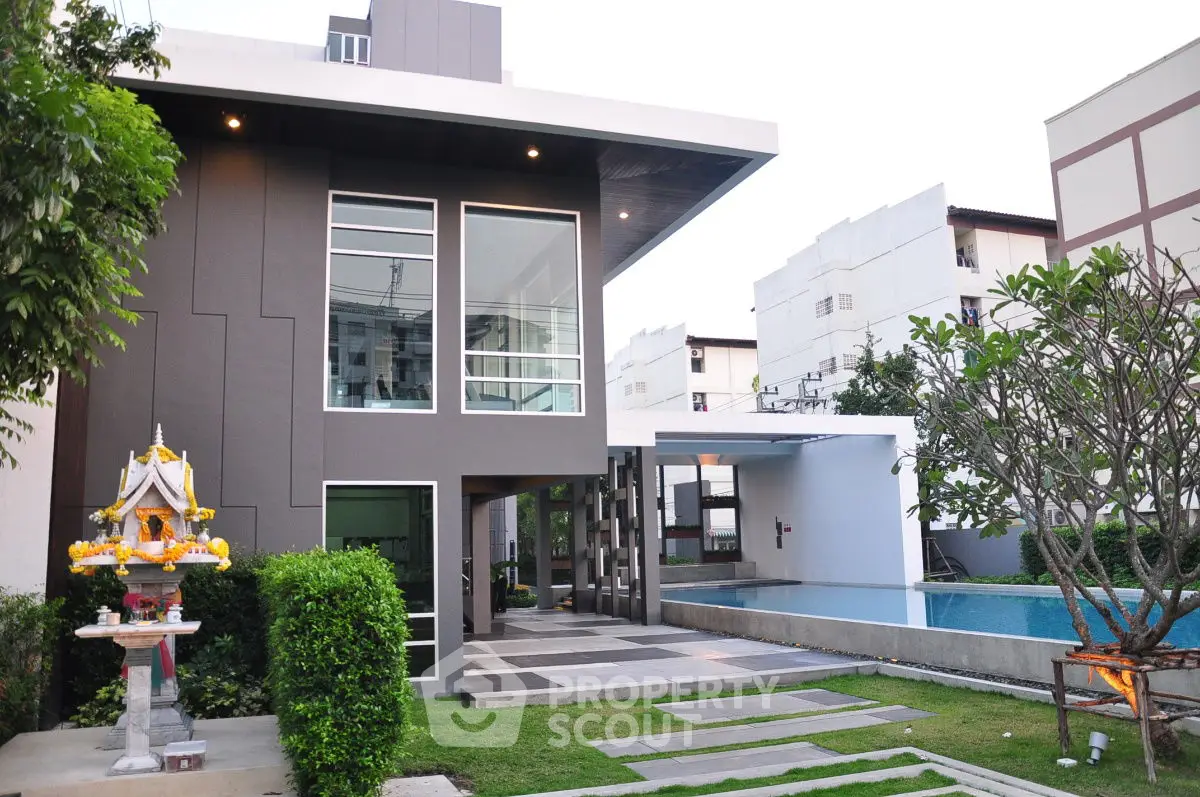 Modern residential building with pool and landscaped garden in urban setting.