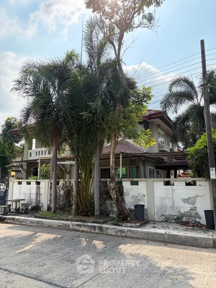 Charming two-story house with lush palm trees and a spacious garden in a serene neighborhood.